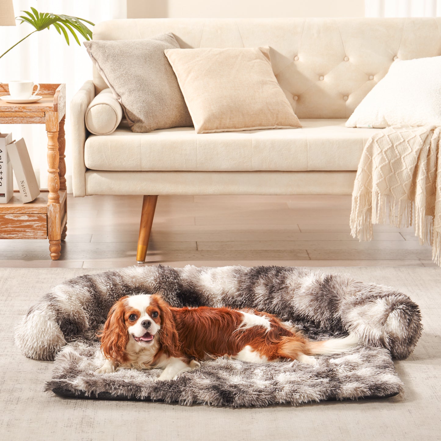 A Cavalier Dog lying on inspaws faux long fur bolster couch cover in ink tie-dye on floor in living room