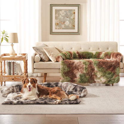 Dog resting on Inspaws faux long fur couch cover in ink tie-dye with green camo sofa protector on couch in living room
